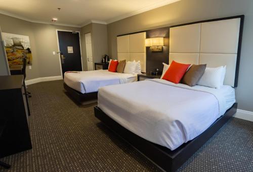 two beds in a hotel room with red pillows at Crowne Plaza Fredericton Lord Beaverbrook by IHG in Fredericton