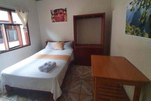 Habitación pequeña con cama y mesa de madera. en Tengana Hospedaje y Tours, en Tarapoto