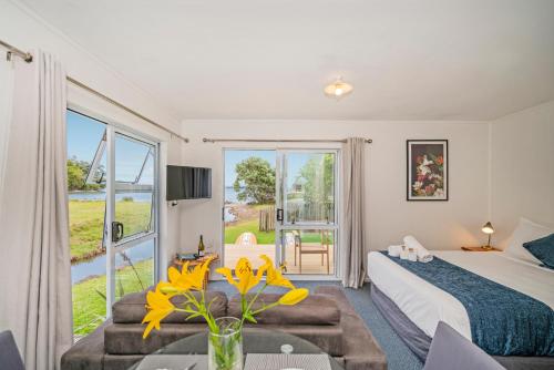 a bedroom with a bed and a large window at Shelly Beach TOP 10 Holiday Park in Coromandel Town