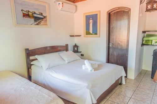 a bedroom with a bed with white sheets at Pousada Bob Pai & Bob Filho in Ilha do Mel