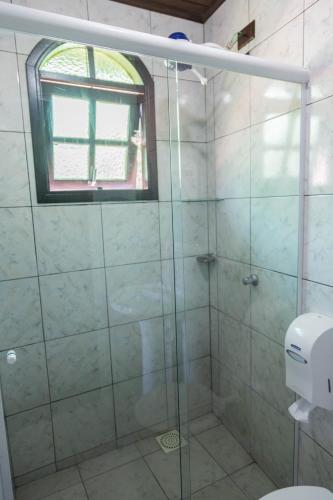 a bathroom with a glass shower with a window at Pousada Bob Pai & Bob Filho in Ilha do Mel