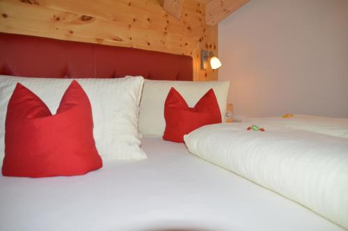 a white bed with red pillows on it at Pension Truya - Hof in Fiss