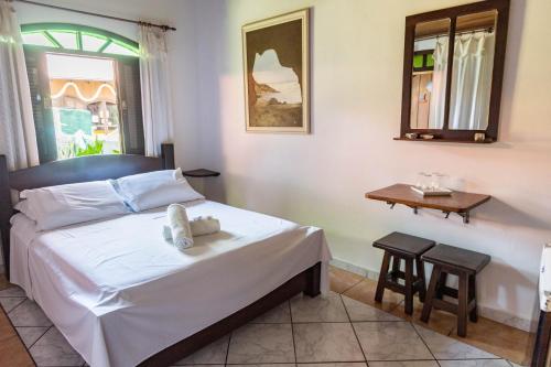 um quarto com uma cama, uma mesa e uma janela em Pousada Bob Pai & Bob Filho na Ilha do Mel