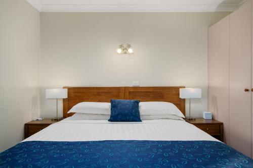 a bedroom with a bed with a blue pillow on it at Stagecoach Motel Wodonga in Wodonga