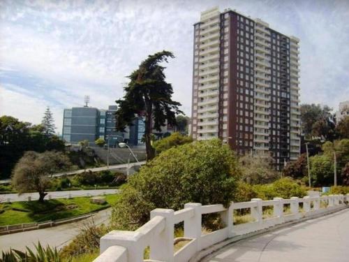 una recinzione bianca di fronte a un palazzo alto di DEPARTAMENTO FRENTE A LA PLAYA 3 personas a Valparaíso