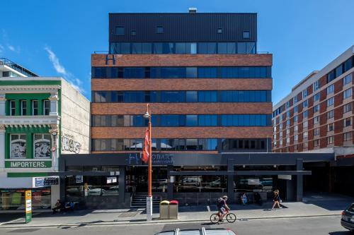 a tall building in a city with people crossing a street at Hobart City Apartments in Hobart