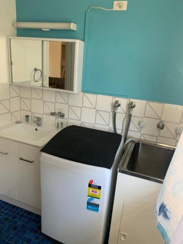 a small kitchen with a sink and a refrigerator at Beachlander Self-Contained Holiday Apartments in Coffs Harbour