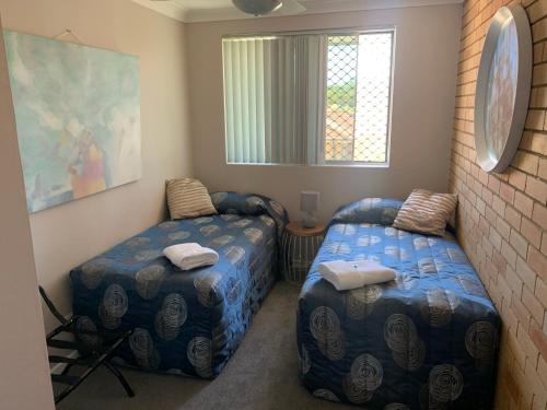 a bedroom with two beds and a window at Beachlander Self-Contained Holiday Apartments in Coffs Harbour