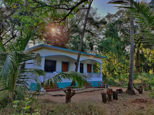 a blue and white house in the middle of trees at Coco inn Goa in Candolim