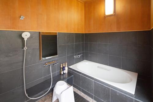 a bathroom with a bath tub and a toilet at Suisui Garden Ryokan (in the Art Hotel Kokura New Tagawa) in Kitakyushu