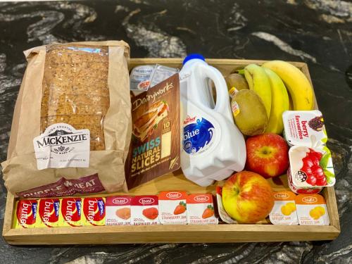 ein Tablett mit Äpfeln, Bananen und anderen Lebensmitteln in der Unterkunft Tairua Shores Motel in Tairua