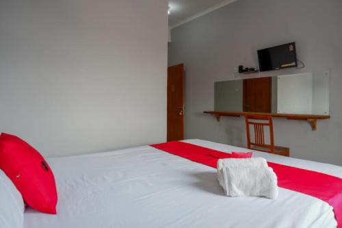 a bedroom with a white bed with red pillows at RedDoorz Syariah near Kawasan Sam Poo Kong 2 in Kalibanteng-kidul