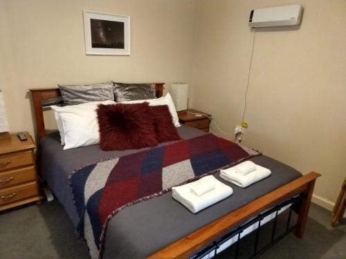 1 dormitorio con 1 cama con 2 toallas en Cockatoo Cabin en Halls Gap