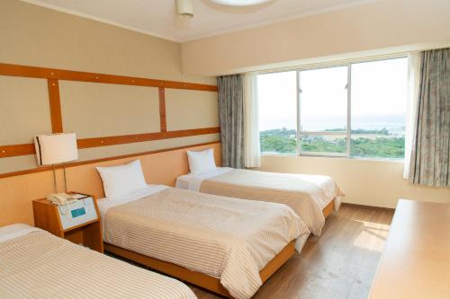 a hotel room with two beds and a window at Motobu Green Park and Golf Course in Motobu