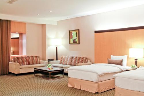 Habitación de hotel con 2 camas y sofá en Queena Plaza Hotel en Yongkang