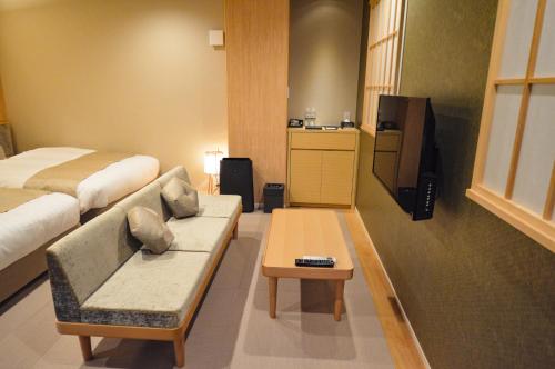 a hotel room with a bed and a couch and a tv at Rinn Horikawa Gojo in Kyoto