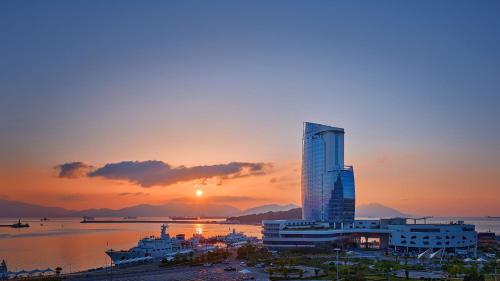 a sunset with a tall building in a city at Sono Calm Yeosu in Yeosu