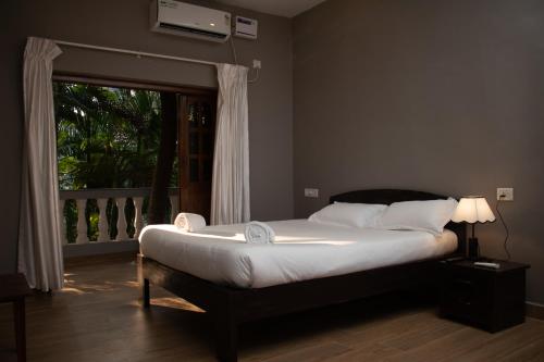 a bedroom with a large bed with a window and a window at The Sovereign Villa in Candolim