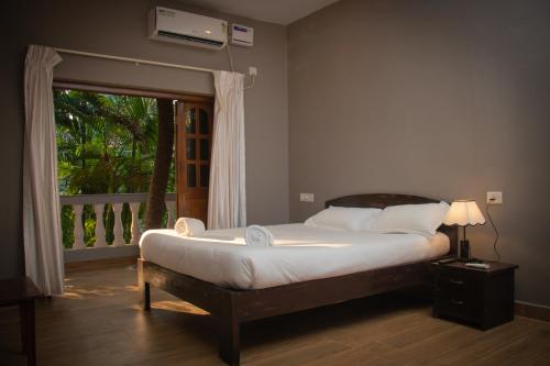 a bedroom with a large bed and a window at The Sovereign Villa in Candolim