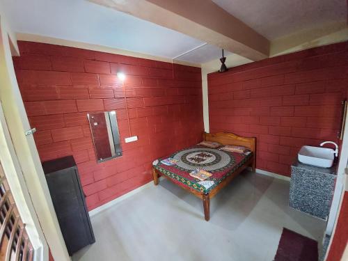 a room with a red wall with a bench in it at Cocopelli Guest House in Gokarna
