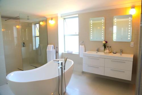 a bathroom with a tub and a shower and a sink at Misty Waves Boutique Hotel in Hermanus