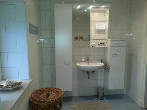 Baño blanco con lavabo y espejo en B&B La Rue de France, en Sevenum