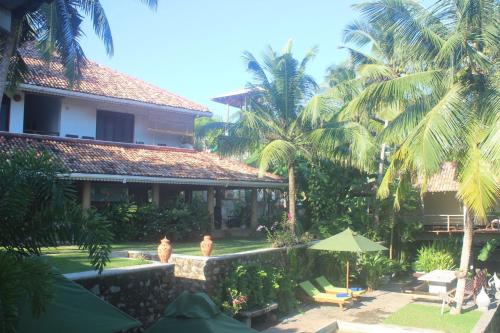 two people standing in front of a building with palm trees at The Spice House Mirissa in Mirissa