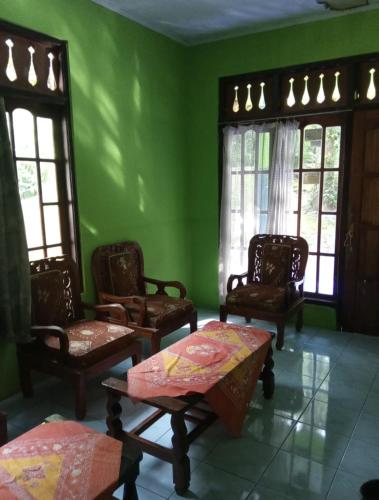 una stanza verde con sedie, un tavolo e finestre di Sri Homestay a Sermo