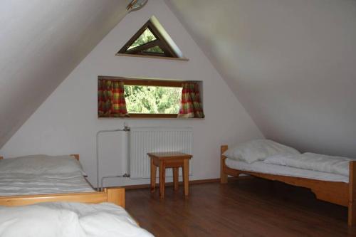 a attic room with two beds and a window at Chata Horáreň in Smižany