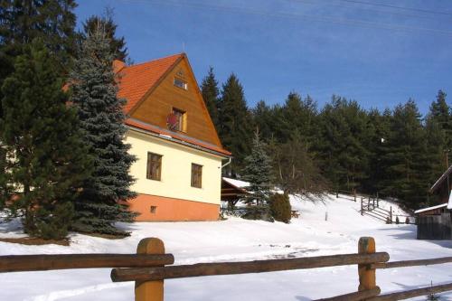 a house in the snow next to a fence at Chata Horáreň in Smižany