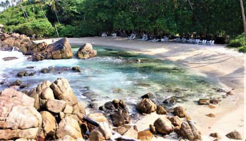 a beach with rocks and chairs on a beach at The Spice House Mirissa in Mirissa