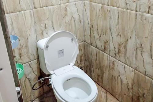 een badkamer met een toilet en een marmeren muur bij Agnes Residence near Blok M Mitra RedDoorz in Jakarta