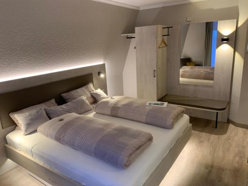 a white bedroom with two beds and a mirror at Apart Hotel Norden in Norden