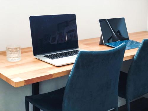 two laptops sitting on a wooden desk with chairs at Wharf Retreat Unit 2 in Tauranga