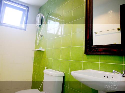 a green tiled bathroom with a toilet and a sink at Ivory Phi Phi Island in Phi Phi Don