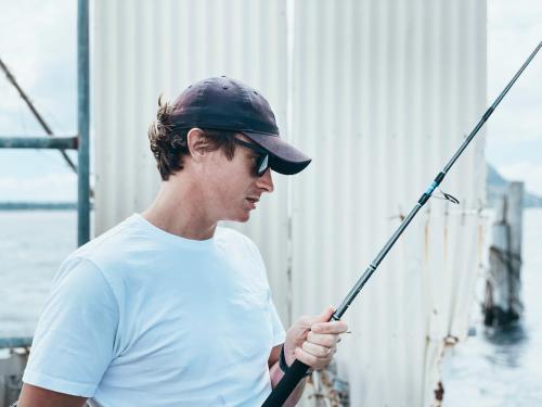 a man wearing a hat holding a fishing pole at Wharf Retreat Unit 2 in Tauranga