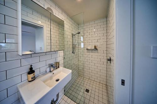 a white tiled bathroom with a sink and a mirror at The Bronte Boutique Hotel in Morpeth