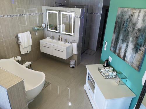 a bathroom with a sink and a toilet and a tub at Misty Waves Boutique Hotel in Hermanus