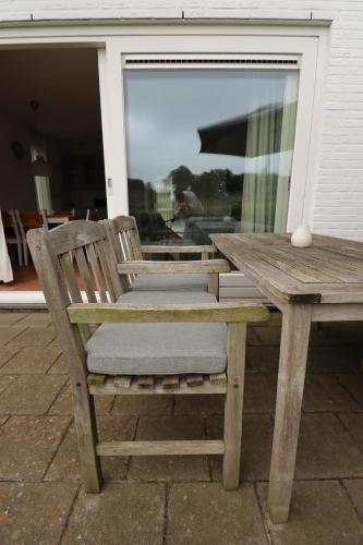 a wooden bench sitting next to a table and a window at Vakantiewoningen Ons Krijtland in Epen