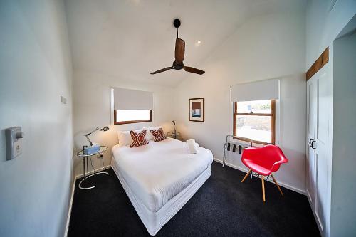 a bedroom with a bed and a red chair at The Bronte Boutique Hotel in Morpeth
