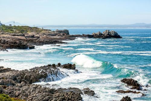 a beach with rocks and waves in the ocean at Misty Waves Boutique Hotel in Hermanus