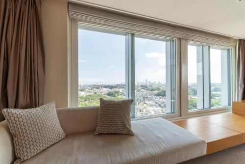 a living room with a couch and large windows at Hotel Associa Shin-Yokohama in Yokohama
