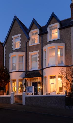 a large brick house with its lights on at Arvon House in Llandudno
