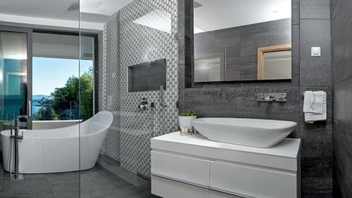 a bathroom with a white tub and a sink at Luxury Beachfront Villa Silvery Moon with private pool, jacuzzi, sauna and gym on Brac island - Sumartin in Selca