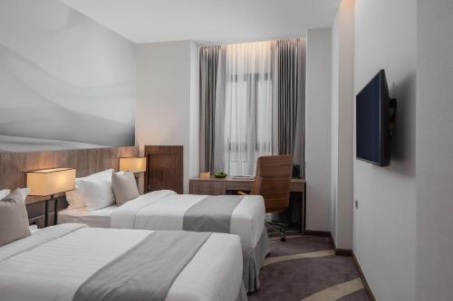 a hotel room with two beds and a television at Sensory Park Urban Hotel in Phnom Penh