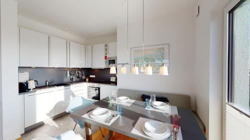 a kitchen with white cabinets and a dining table at Seeblick Strandgold, exklusive Wohnung mit Meerblick in Wangerooge