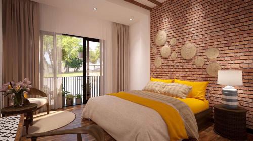 a bedroom with a yellow bed and a brick wall at Banana Flower Homestay in Danang