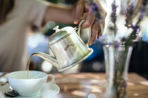 una persona vertiendo café en una taza sobre una mesa en Tirolerhof, en San Leonardo in Passiria