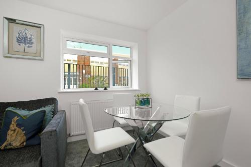 a dining room with a glass table and white chairs at St Martins 2 Bedroom Apartments in Ruislip By 360 Stays in Ruislip