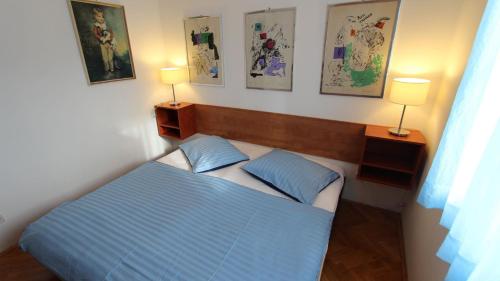 sypialnia z łóżkiem oraz 2 lampami i obrazami na ścianie w obiekcie Apartment Rolih w mieście Vantačići
